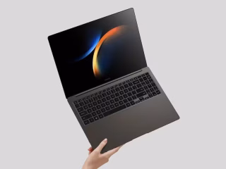 Mão segurando um laptop Galaxy Book3 Ultra em um fundo cinza.