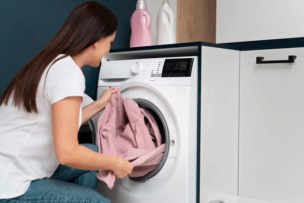 Uma Mulher colocando roupas em uma maquina de lavar roupas - Maquinas de lavar roupas smart