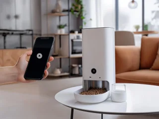 Cafeteira smart e uma mão segurando um smartphone.