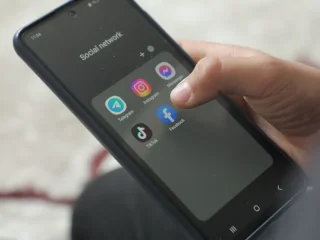 Mão segurando um smartphone exibindo tela de Apps.