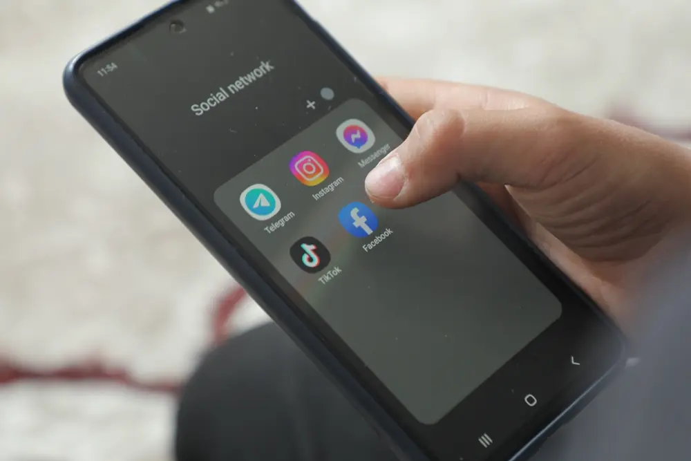 Mão segurando um smartphone exibindo tela de Apps.