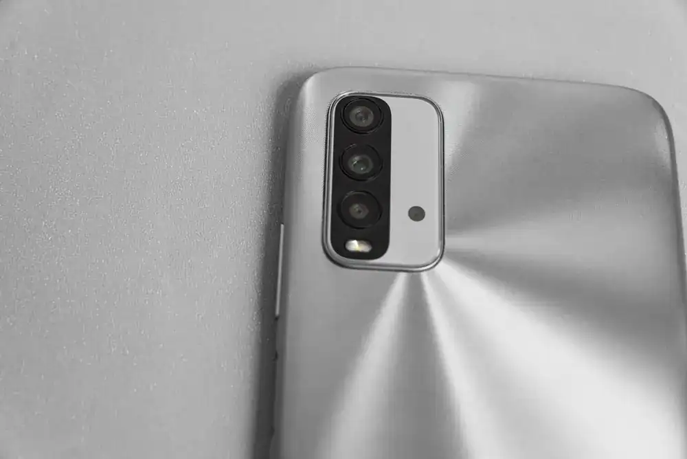 Conjunto triplo de câmeras traseiras em smartphone intermediário.