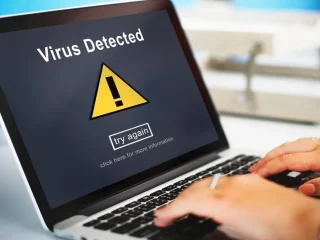 Uma pessoa com um notebook exibindo uma mensagem de vírus na tela. Como proteger o PC de vírus