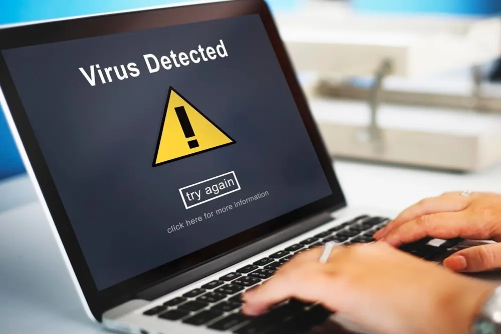 Uma pessoa com um notebook exibindo uma mensagem de vírus na tela. Como proteger o PC de vírus
