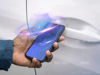 Uma mão segurando um smartphone com o símbolo de um escudo na tela.
