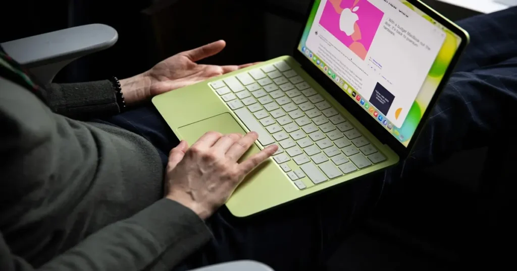 MacBook Neo da Apple ao lado de laptops da Asus e Dell. Alt Text: "MacBook Neo da Apple desafia fabricantes de PC