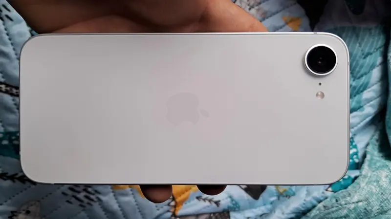 iphone 16 vs iphone 16e, Mão segurando um iphone 16e cor branca. 