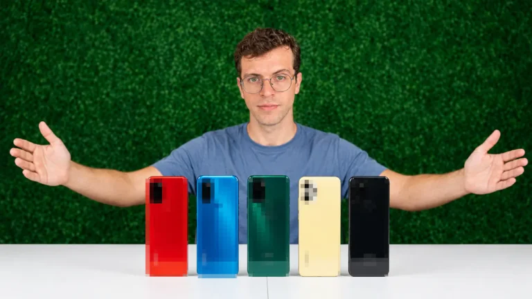 Uma pessoa cabelo cacheado curto usando oculos, atrás de um balcão com 5 Celular Gamer Baratos dispostos