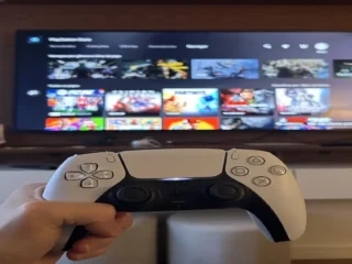 DRM Playstation, mão segurando joystick dual shock cor branco ao fudo tela inicial jogo.