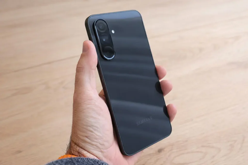 Celular Samsung Galaxy A36, cor preto, em um fundo mesa de madeira em tons claros.