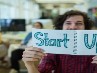 uma pessoa segurando um card com a palavra Startup escrita.