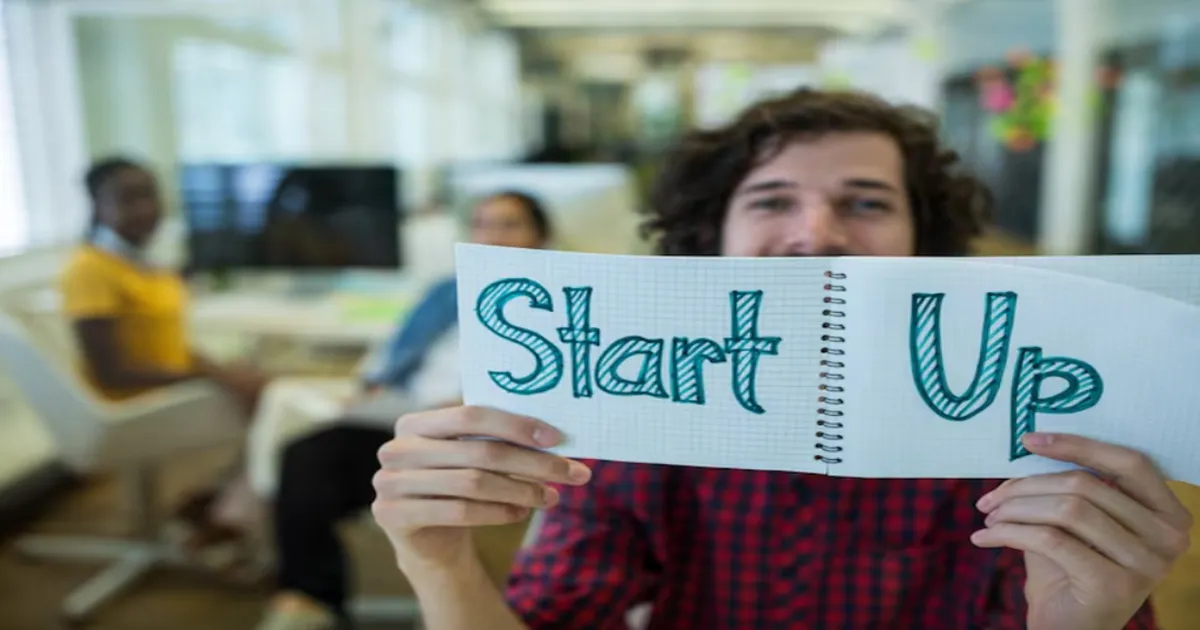 uma pessoa segurando um card com a palavra Startup escrita.