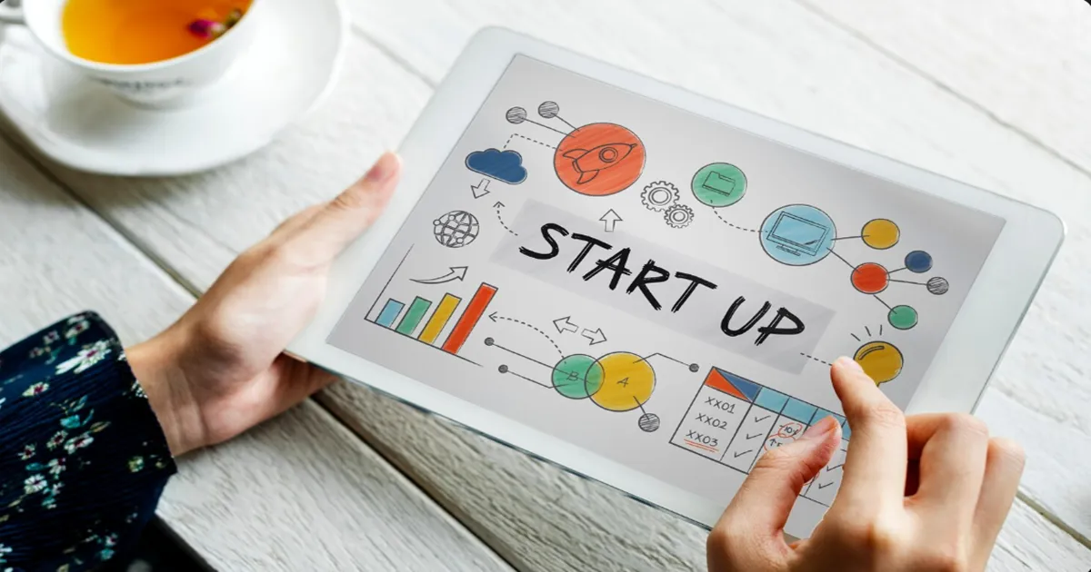 Mãos segurando uma placa escrito startup