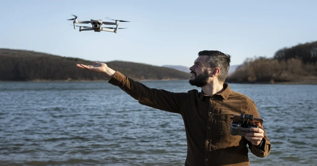 Uma pessoa em um ambiente externo, com um controle remoto e um drone DJI voando.