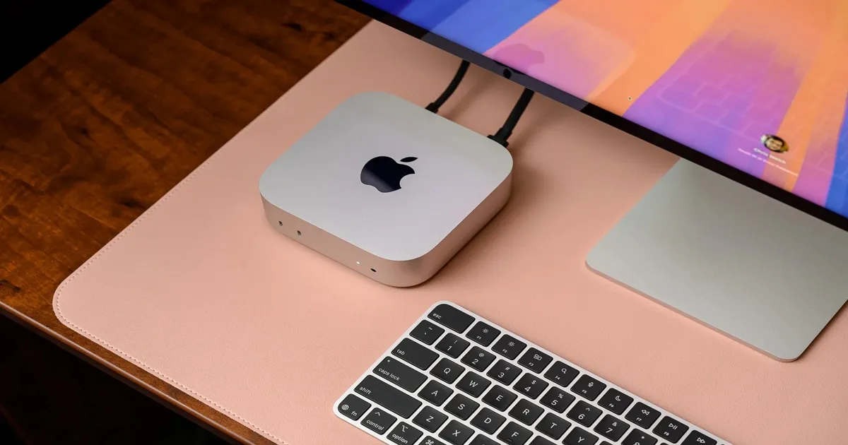 Apple Mac Mini sobe uma mesa de madeira com teclado e um tela.
