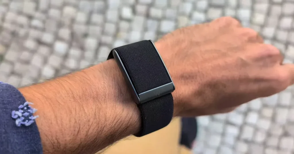 Pulseira Whoop no pulso em um fundo desfocado.