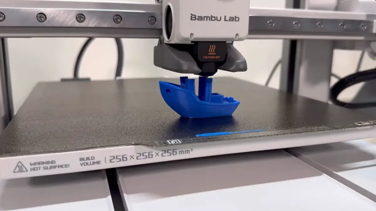 Bambu Lab A1 vale a pena? Veja por que ela virou referência 2 Impressora Bambulab imprimindo um barco azul.