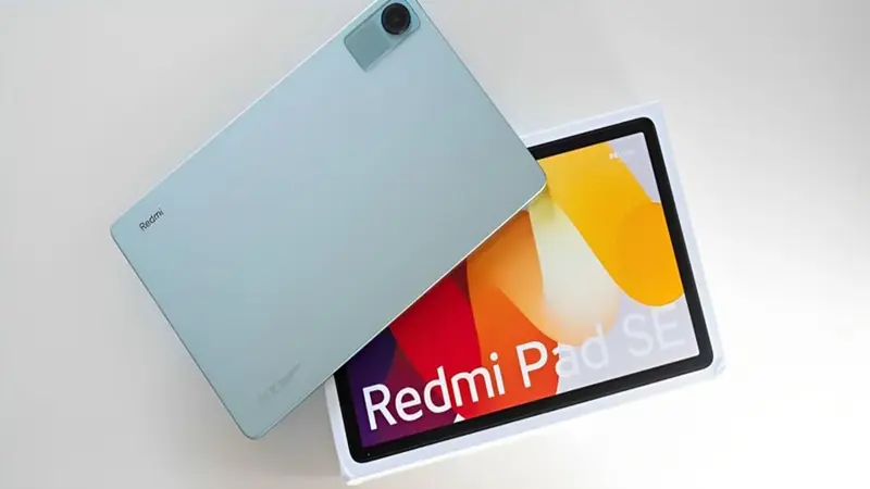 Tablet Redmi pad SE cor azul sobre uma mesa branca e ao lado de sua caixa.
