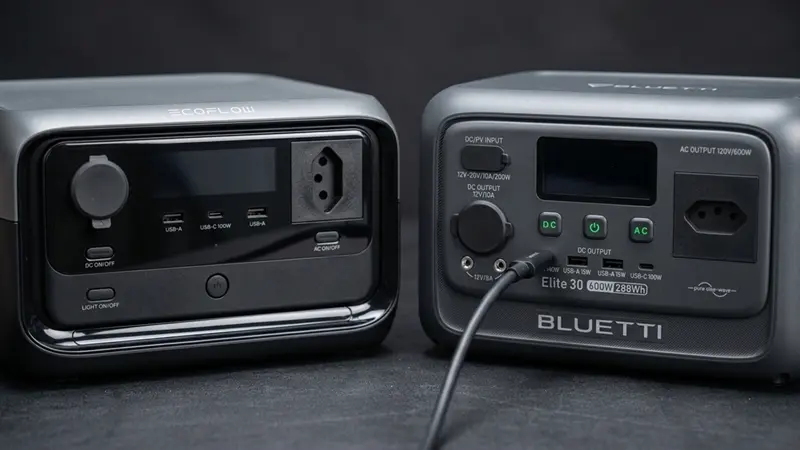 Painéis frontais da BLUETTI Elite 30 V2 e da EcoFlow River 3 Plus lado a lado na bancada, mostrando suas portas USB e outras conexões.