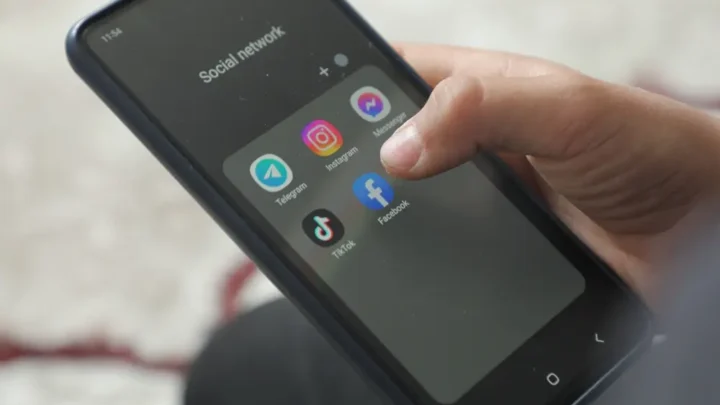 Mão segurando um smartphone exibindo tela de Apps.