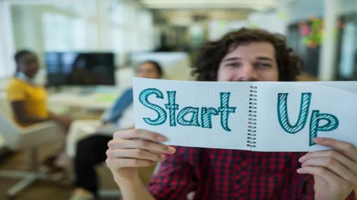 uma pessoa segurando um card com a palavra Startup escrita.