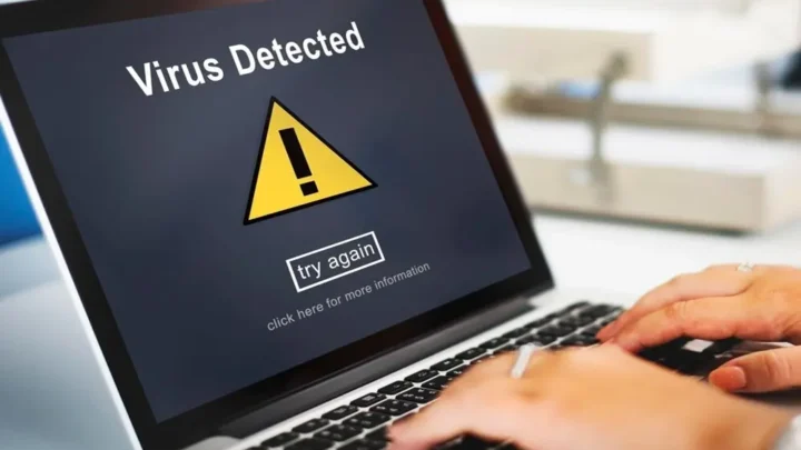 Uma pessoa com um notebook exibindo uma mensagem de vírus na tela. Como proteger o PC de vírus