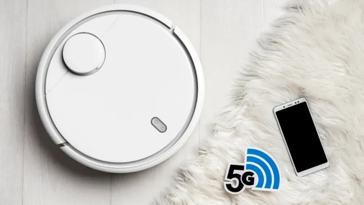 Robô aspirador cor branco ao lado de um tapete cor branco e um smartphone.